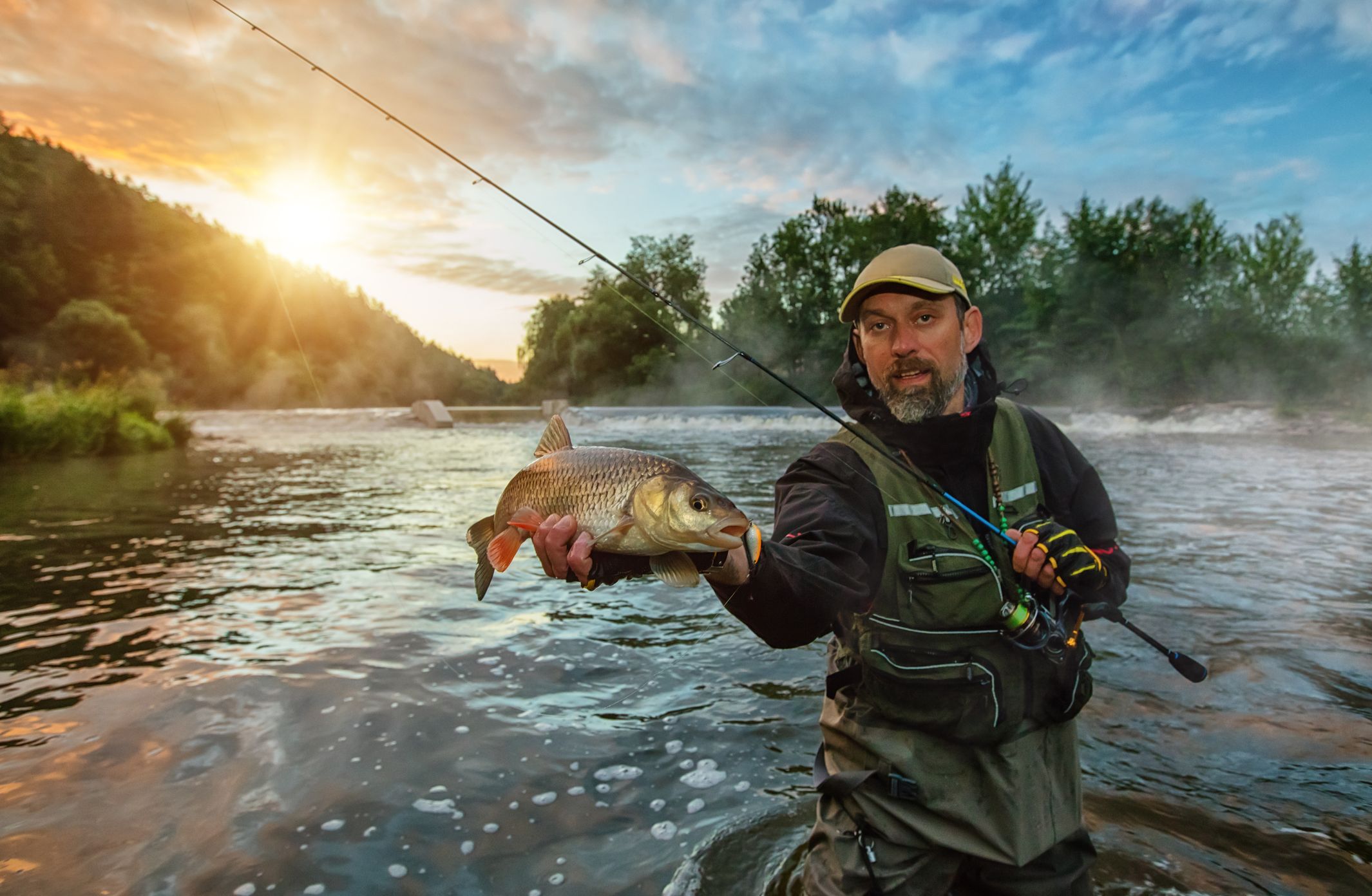 Angler with a catch on a BC river at sunset